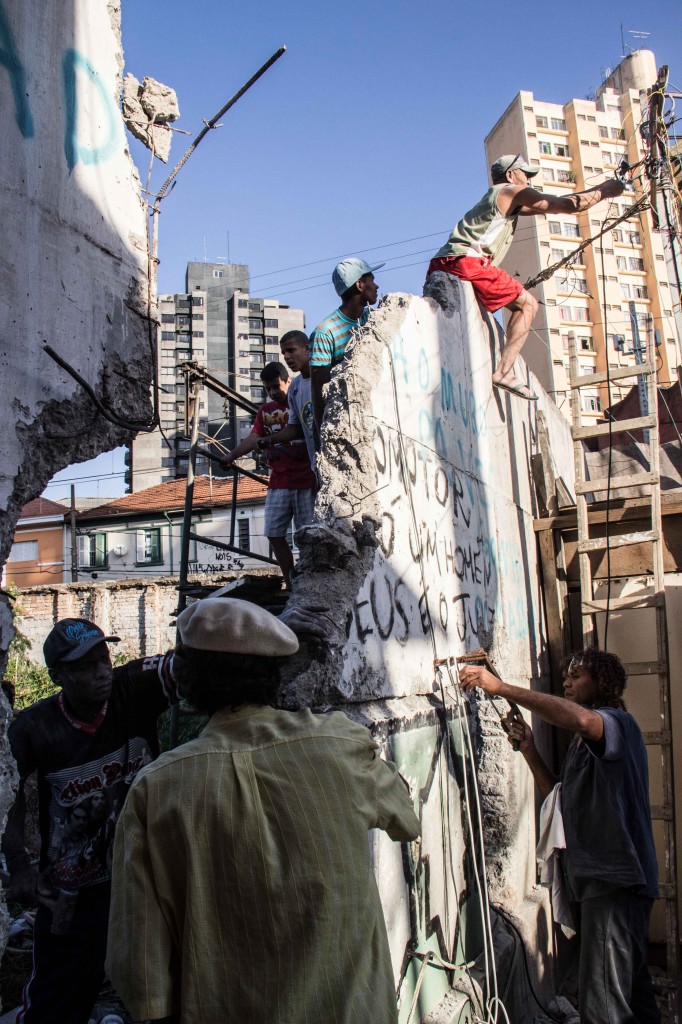Moradores em cima do muro, trabalhando na demolição.