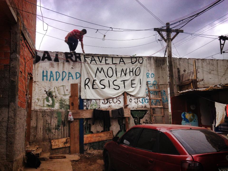 Com 55 metros de extensão, o muro erguido por Kassab divide a favela em duas: de um lado, os escombros de cinza dos barracos destruídos em 2011 pelo primeiro grande incêncio e o entulho do prédio demolido no mesmo ano. Do outro lado, as casas que não foram atingidas pelas chamas. Esta parte do muro que se vê é a única que pode ser derrubada para criação da rota de fuga, já que o restante da estrutura serviu de apoio às novas casas construídas. Foto/Associação Moinho Vivo
